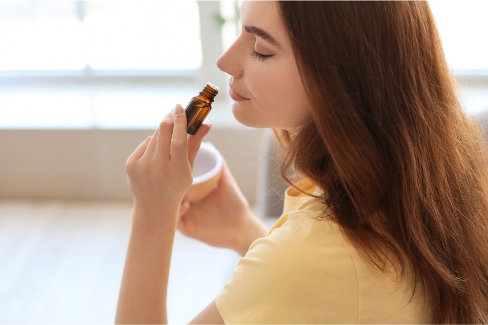 Femme se détendant avec des huiles essentielles et un diffuseur dans un cadre cosy