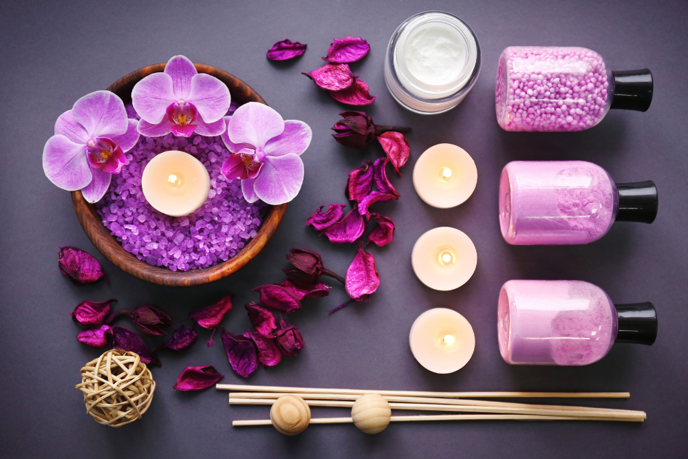 Composition d'aromathérapie avec des orchidées violettes, des bougies allumées, du sel et des huiles essentielles
