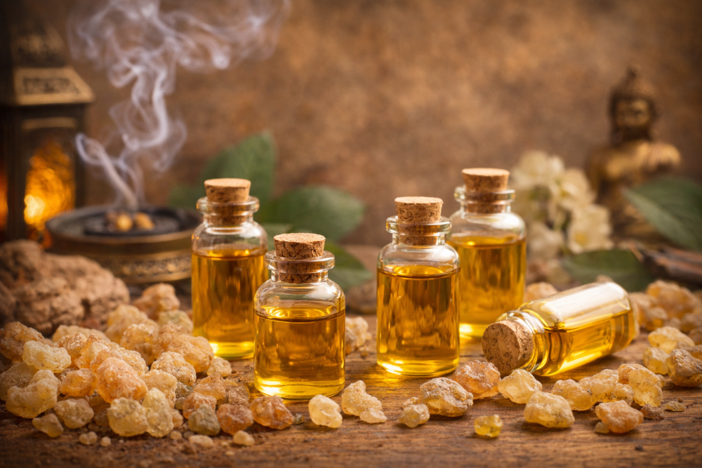 Huiles essentielles d'encens dans de petits flacons en verre entourés de morceaux de résine d'encens sur un support en bois naturel