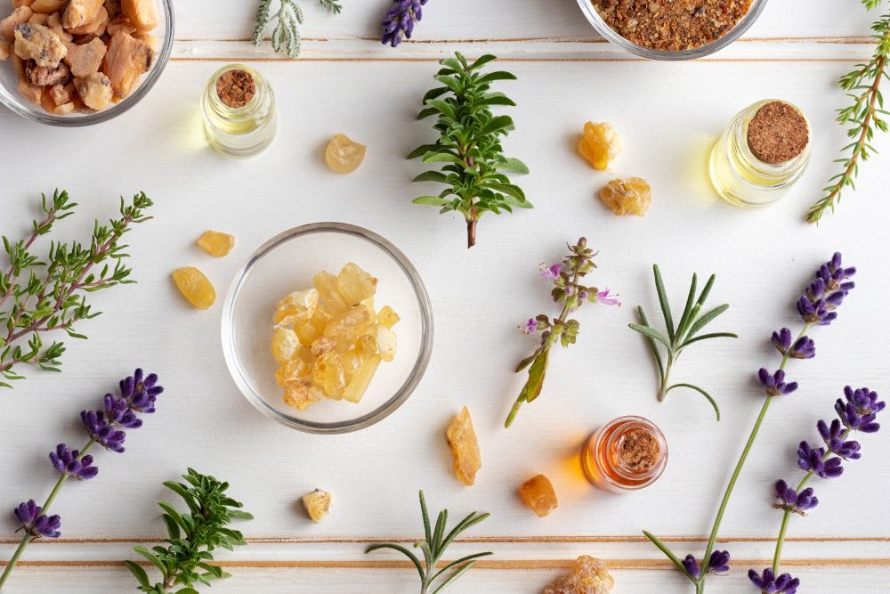 Flacons d'huiles essentielles entourés d'herbes fraîches et de fleurs pour l'aromathérapie