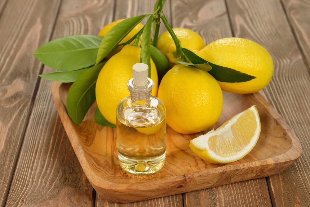 Huile de citron en petit flacon avec des citrons frais sur un support en bois