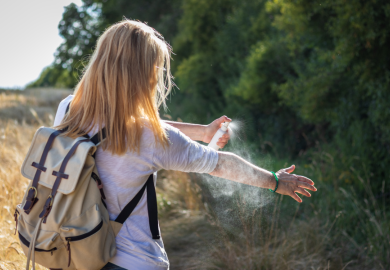 Femme utilisant un spray naturel contre les moustiques en plein air