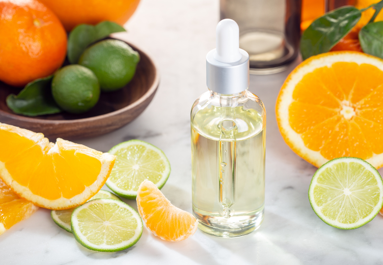 Flacon d'huile essentielle de citron parmi des tranches d'agrumes frais – un produit naturel pour le ménage sans chimie.