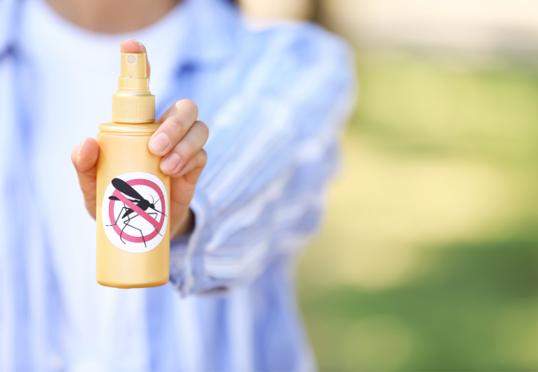 Personne tenant un spray répulsif contre les moustiques en extérieur.